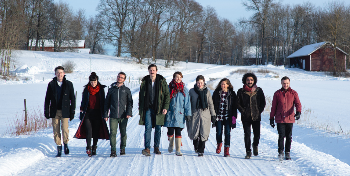 Photo of nine artists in residence at Saari, Finland, walking down a snowy road in the countryside