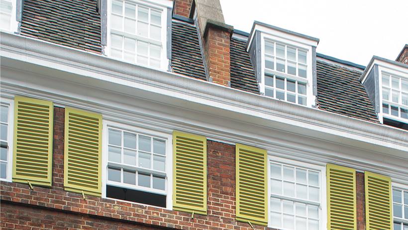 Upper floors of a British terrace house, including roof, with windows and shutters.